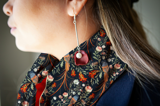 A close up of the silk scarf features the South African Flycatcher bird with it's long, elegant tail feathers within the protea, lion's tail, and wild roses. 